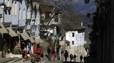 Orang-orang berjalan-jalan di kota Gjirokastra, Albania selatan pada 5 Februari 2021. Pariwisata telah berkembang di kota Gjirokastra, yang diakui sebagai Situs Warisan Dunia UNESCO, tetapi pandemi virus corona menghentikannya secara tiba-tiba. (AP Photo/Hektor Pustina)