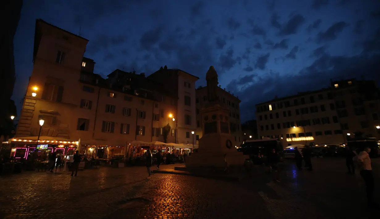 Orang-orang duduk di restoran saat matahari terbenam, di lingkungan Campo dei Fiori Roma, Senin (26/4/2021). Italia kembali dibuka secara bertahap pada hari Senin setelah enam bulan memberlakukan lockdown untuk menghambat penyebaran corona Covid-19. (AP Photo/Alessandra Tarantino)
