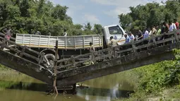 Petugas penyelamat dan penduduk desa India berkumpul di dekat jembatan yang runtuh di desa Phasidewa dekat perbatasan India-Bangladesh di pinggiran Siliguri di negara bagian India, Bengal Barat (7/9). (AFP Photo/Diptendu Dutta)