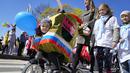 Seorang anak mengendarai sepeda yang menggambarkan helikopter selama perayaan peringatan 318 tahun kota Kronstadt, di luar St. Petersburg, Rusia (21/5/2022). (AP Photo/Dmitri Lovetsky)