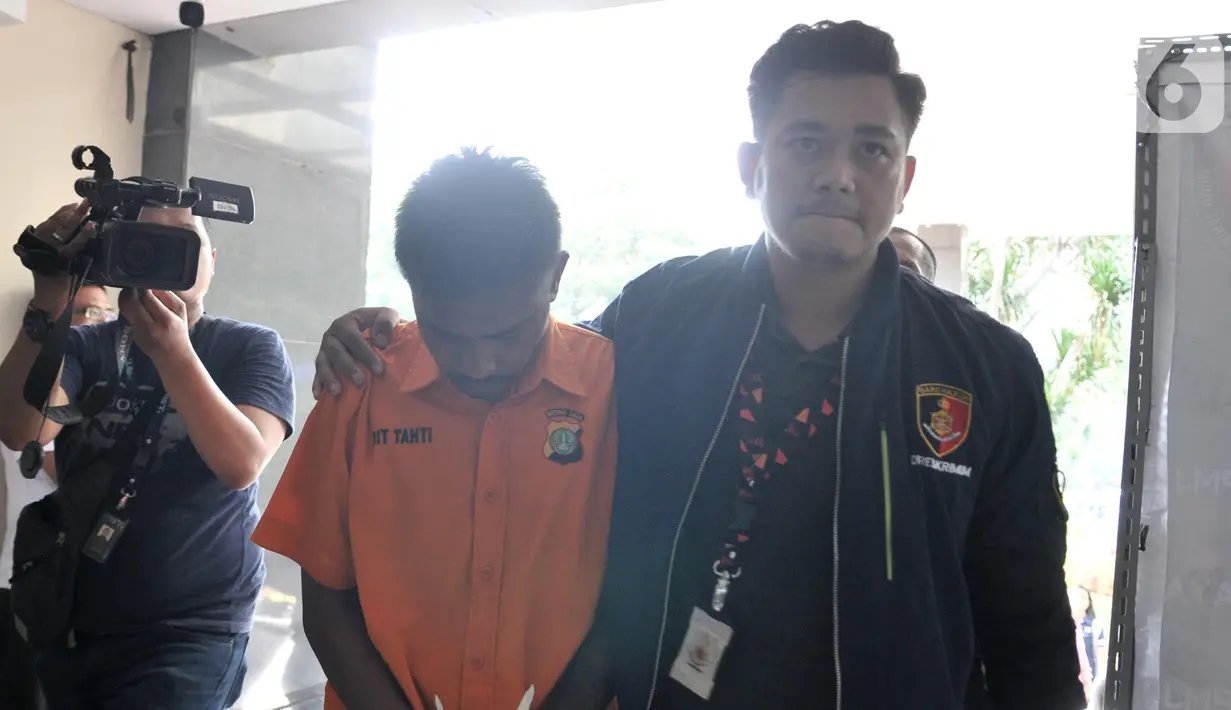 Polisi (kanan) menggelandang tersangka kasus pembunuhan Rieke Andrianti saat dihadirkan dalam rilis di Mapolda Metro Jaya, Jakarta, Senin (11/11/2019). Tersangka JE yang juga tetangga korban nekat membunuh Rieke Andrianti lantaran sakit hati akibat sering diejek. (merdeka.com/Iqbal Nugroho)