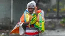 Seorang pria menutupi dirinya dengan plastik saat berjalan di sepanjang jalan di Amreli setelah siklon Tauktae menghantam pantai barat India pada Selasa (18/5/2021). Topan Tauktae disebut yang terbesar melanda wilayah itu dalam beberapa dekade terakhir. (Punit PARANJPE / AFP)