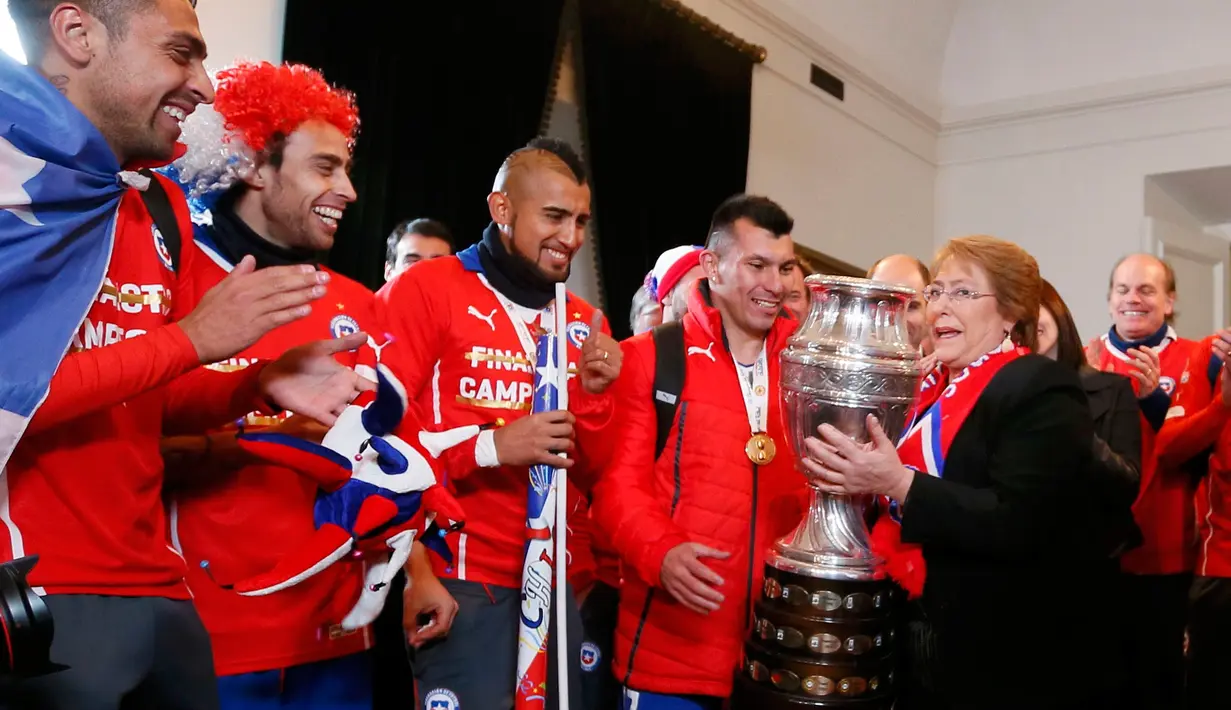 Pemain Chile memberikan trofi pada Presiden Chili, Michelle Bachelet usai mengalahkan Argentina di final Copa America 2015 di Istana nasional, Chili (4/7/2015). Chili menang lewat adu penalti atas Argentina dengan skor 4-1. (REUTERS/Rodrigo Garrido)