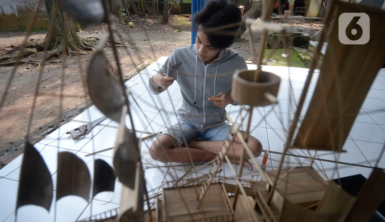 Perajin menyelesaikan pembuatan miniatur kapal pinisi yang terbuat dari limbah bambu di Pondok Benda, Pamulang, Tangerang Selatan, Senin (09/11/2020). Kerajinan berbahan bambu bekas yang dijual dengan harga berkisar Rp.50 ribu hingga Rp.250 ribu tergantung ukurannya. (merdeka.com/Dwi Narwoko)