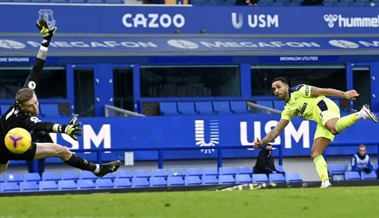 Pemain Newcastle United Callum Wilson (kanan) mencetak gol ke gawang Everton yang dijaga Jordan Pickford pada pertandingan Liga Inggris di Goodison Park, Liverpool, Inggris, Sabtu (30/1/2021). Newcastle United menang 2-0. (Paul Ellis/Pool via AP)