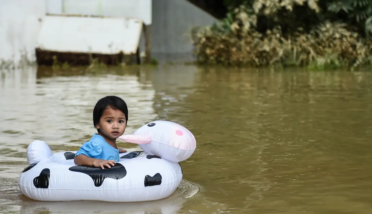 Seorang anak bermain saat banjir melanda kawasan Rantau Panjang, Malaysia, Kamis (5/1). Sekitar 23 ribu orang terpaksa mengungsi karena banjir yang disebabkan hujan muson ini. (AFP PHOTO / MOHD RASFAN)