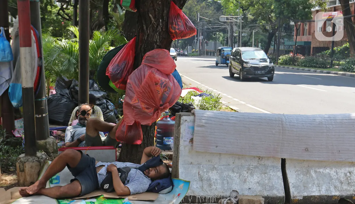 Pencari suaka beristirahat di trotoar kantor UNHCR, Jalan Kebon Sirih, Jakarta, Sabtu (1/5/2021). Para pencari suaka itu menuntut Komisi Tinggi PBB untuk Pengungsi (UNHCR) meminta kejelasan atas status dan memperhatikan nasib mereka selama hidup di Indonesia. (Liputan6.com/Herman Zakharia)