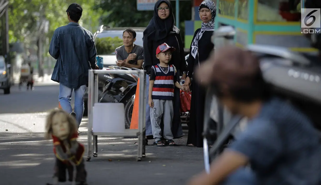 Pengguna jalan melihat monyet menampilkan kebolehan saat atraksi topeng monyet di kawasan Abdul Rachman Saleh, Jakarta, Sabtu (31/3). Bagi para penentangnya, pertunjukan topeng monyet dianggap melanggar etika terhadap hewan. (Liputan6.com/Faizal Fanani)