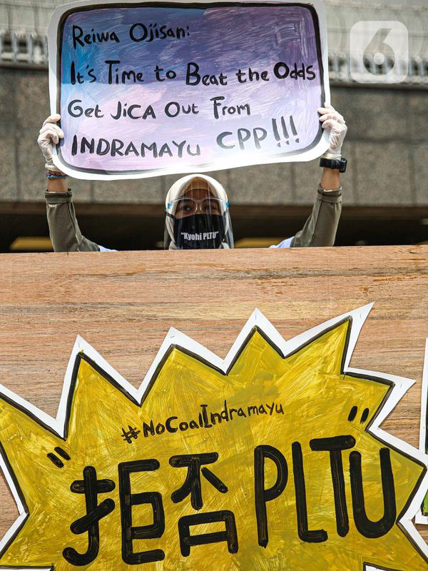 Seorang warga dari Indramayu membawa poster saat menggelar aksi di depan Kedubes Jepang, Jakarta, Rabu (21/10/2020). Dalam aksinya, mereka menolak pembangunan PLTU 2 di Indramayu karena akan menyebabkan pencemaran udara dan rusaknya lahan pertanian. (Liputan6.com/Faizal Fanani)
