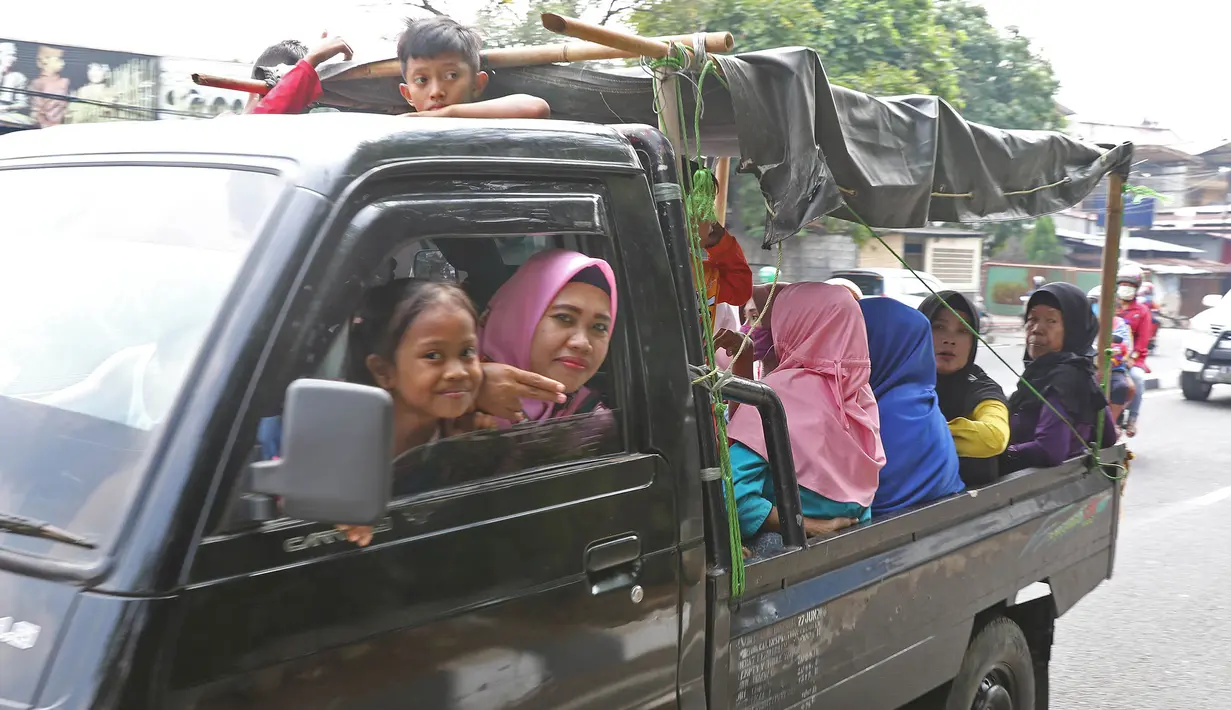 Sejumlah warga berpergian dengan menggunakan mobil bak terbuka di kawasan Jakarta, Minggu (9/6/2019). Warga memanfaatkan truk dan mobil bak terbuka untuk bepergian bersama keluarga menuju sejumlah objek wisata karena dianggap lebih hemat biaya. (Liputan6.com/Herman Zakharia)