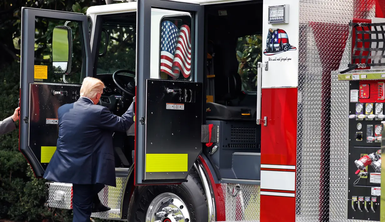 Presiden AS, Donald Trump mencoba menaiki sebuah truk pemadam kebakaran saat bersama Wapres Mike Pence menghadiri acara pameran produk bertajuk "Made in America" di Gedung Putih, Washington, Senin (17/7). (AP Photo/Alex Brandon)