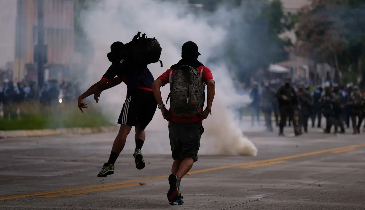 Para pengunjuk rasa melempar batu ke polisi anti huru-hara saat melakukan aksi protes pada peringatan Hari Buruh di San Juan, Puerto Rico (1/5). Hari Buruh yang jatuh pada tanggal 1 Mei ini diperingati di berbagai negara. (AFP/Ricardo Arduengo)