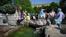 Orang-orang menikmati musim semi yang panas dekat air mancur di luar Kremlin, Moskow, Rusia, Selasa (18/5/2021). Suhu di Moskow telah mencapai 31 derajat Celcius. (Natalia KOLESNIKOVA/AFP)