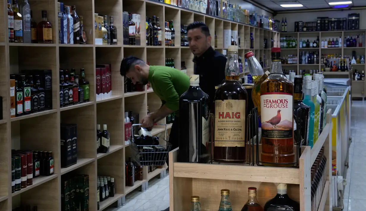 Sejumlah pembeli memilih alkohol di sebuah toko minuman keras di Baghdad, Irak, Kamis, 9 Maret 2023. Dalam sebuah pernyataan, Otoritas Umum Bea Cukai Irak mengatakan seluruh titik pabean diperintahkan melarang masuk segala jenis minuman beralkohol. (AP Photo/Hadi Mizban)