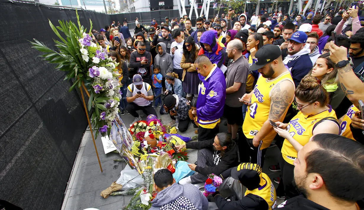 Fans LA Lakers tampak sedih saat berkumpul di Staples Center, Minggu (26/1/2020). Legenda basket NBA, Kobe Bryant, wafat dalam kecelakaan helikopter di Calabasas, California. (AP/Matt Hartman)