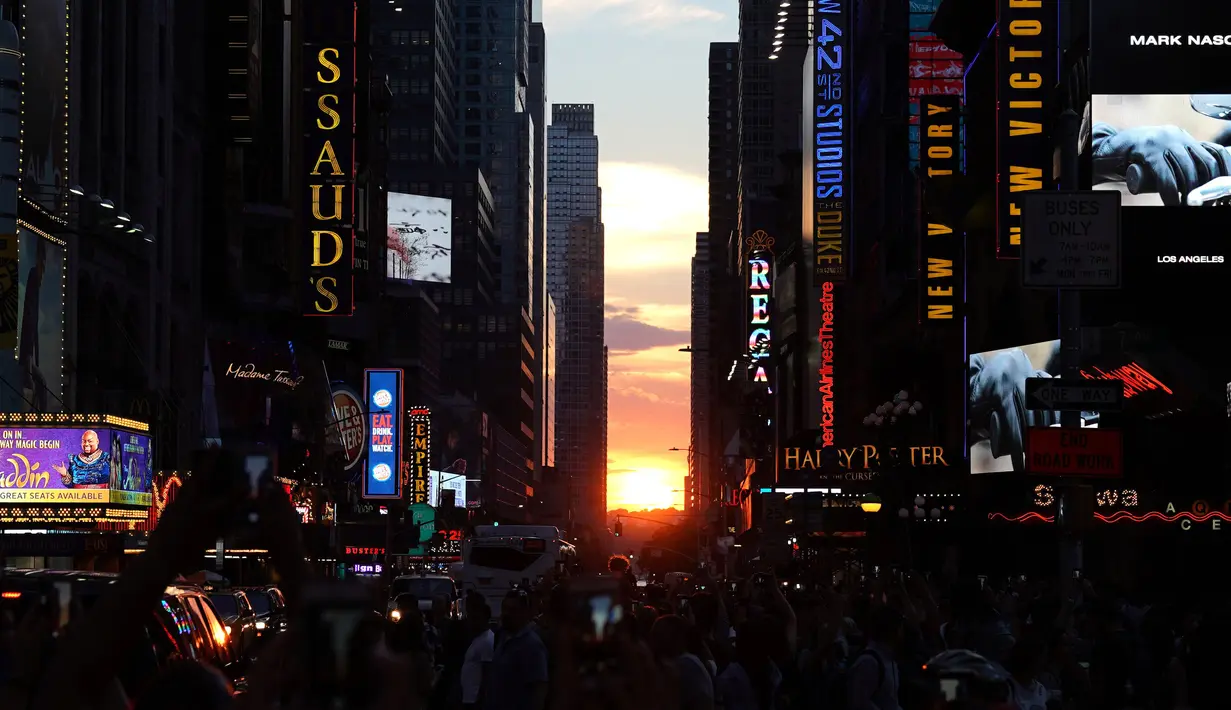 Matahari terbenam di antara pencakar langit, sejajar tepat dengan jalan, ketika fenomena Manhattanhenge di 42nd street di Times Square, New York City, Kamis (12/7). Fenomena ini hanya terjadi selama beberapa hari dalam setahun. (AFP/TIMOTHY A. CLARY)