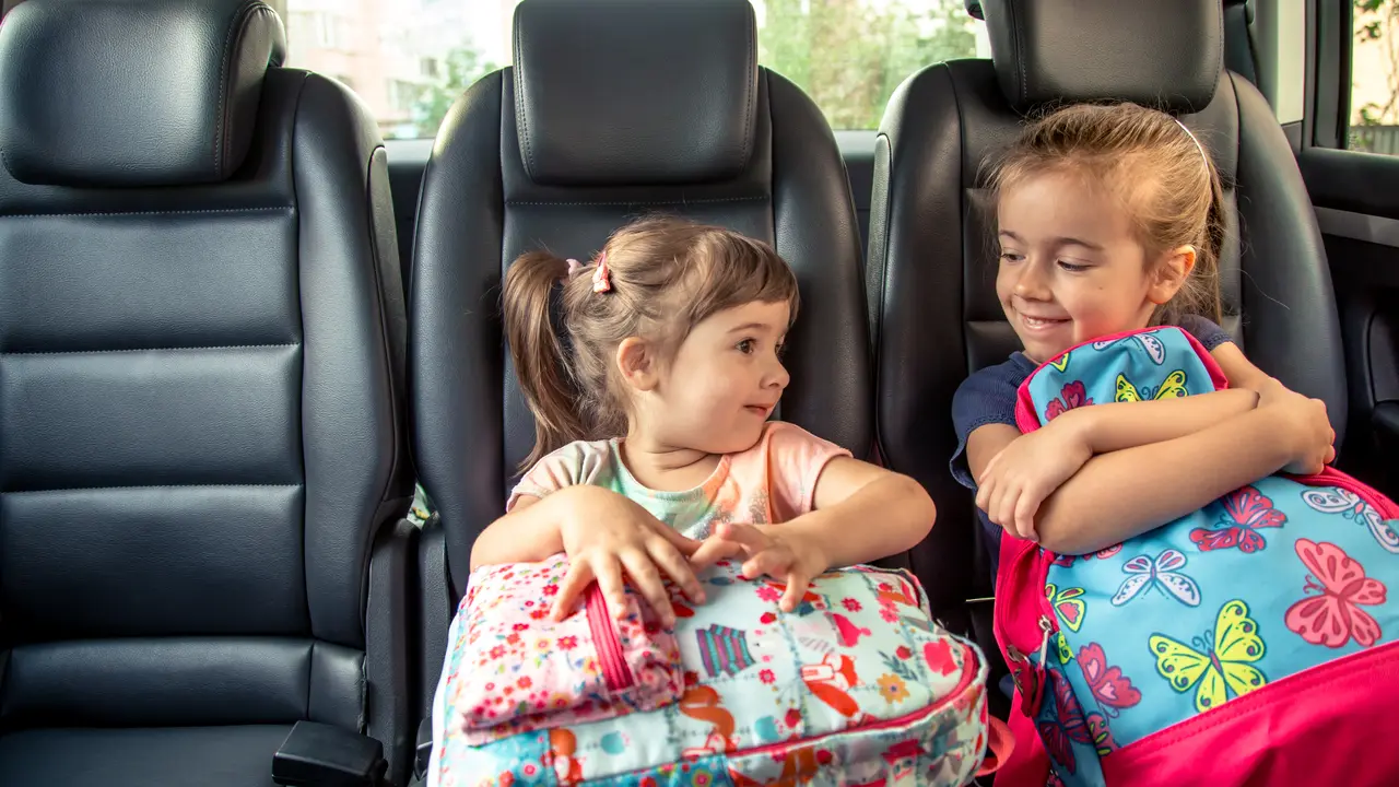 Dua orang anak perempuan memegang tas ransel di dalam mobil (Foto Dok: Freepik/pvproductions)