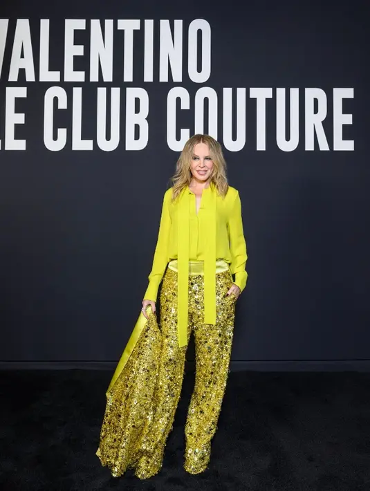 Tampil serba kuning, Kylie Minogue mengenakan kemeja dipadukan celana dan blazer berpayet. Ia mengenakan koleksi Spring Summer 2023 Unboxing. Dipadukan sepatu  Valentino Garavani. Credit: Valentino/SGP Italia