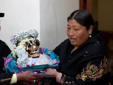 Wanita membawa tengkorak manusia yang dihias usai berdoa di kapel Pemakaman Umum selama Festival Natitas di La Paz, Bolivia (8/11). Ritual ini digelar setiap tahunnya di Bolivia. (AP Photo/Juan Karita)