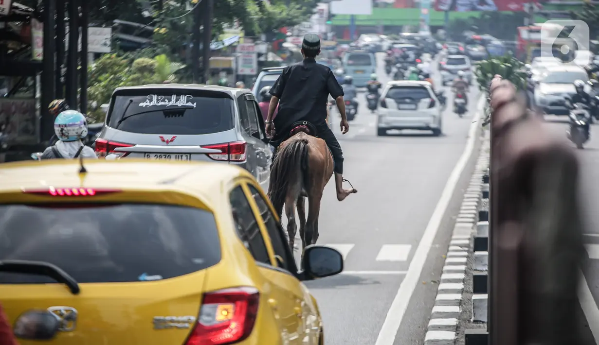 Seorang pria terlihat menunggangi kuda usai melaksanakan sholat Jumat di kawasan Jalan Raya Kramat Jati, Jakarta, Jumat (23/6/2023). (Liputan6.com/Faizal Fanani)