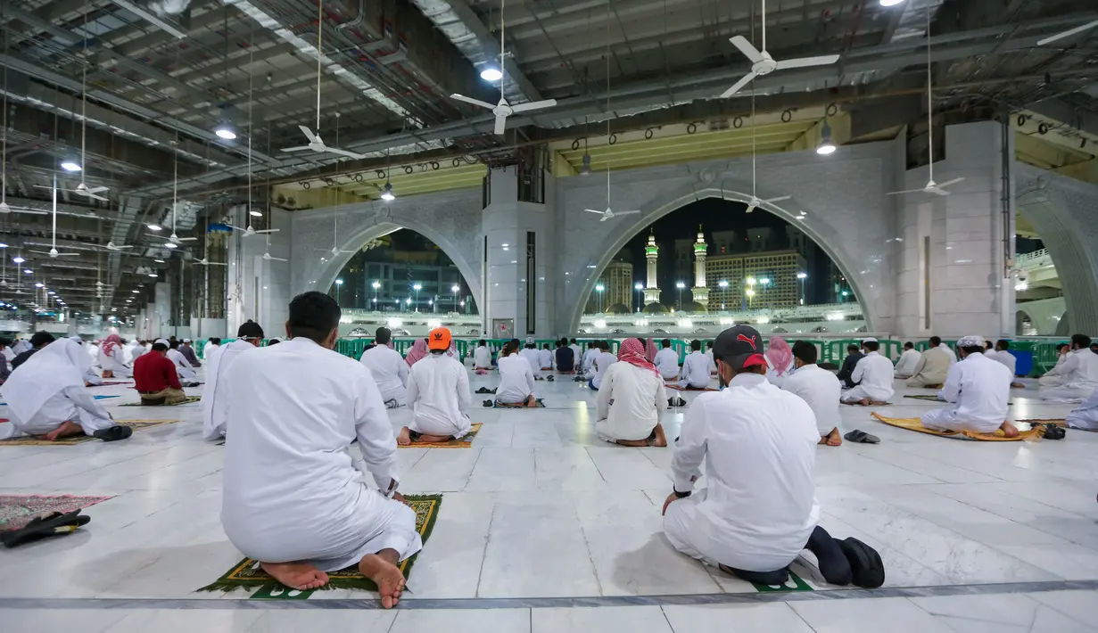 Warga Saudi dan ekspatriat melakukan sholat "Al Fajr" di Masjidil Haram di kota suci Mekkah (18/10/2020). Salat di Masjidil Haram ini dilaksanakan dengan menerapkan protokol kesehatan ketat untuk mengantisipasi penularan virus, seperti pemakaian masker dan menjaga jarak fisik. (AFP/STR)