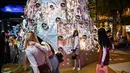 Orang-orang berfoto dengan dekorasi Natal di depan pusat perbelanjaan di Bangkok (21/12/2021). Menyambut Natal, dekorasi unik dan lucu ditampilkan di depan pusat perbelanjaan di Bangkok. (AFP/Lillian Suwanrumpha)