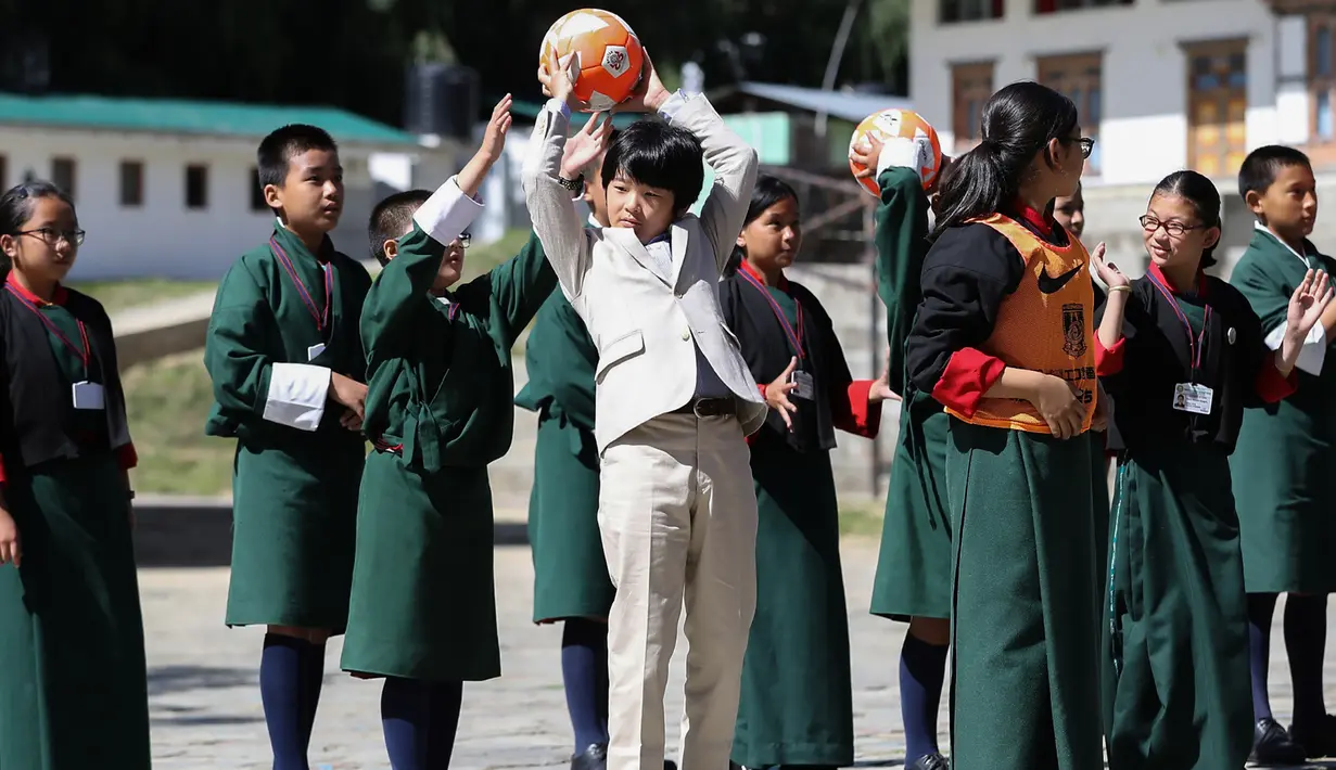 Pangeran Hisahito (tengah) berusia 12 tahun dari Jepang mengoper bola saat bermain bersama siswa setempat saat mengunjungi sebuah sekolah di Thimpu, Bhutan, Selasa (20/8/2019). (AFP Photo/Japan Out/Jiji Press)