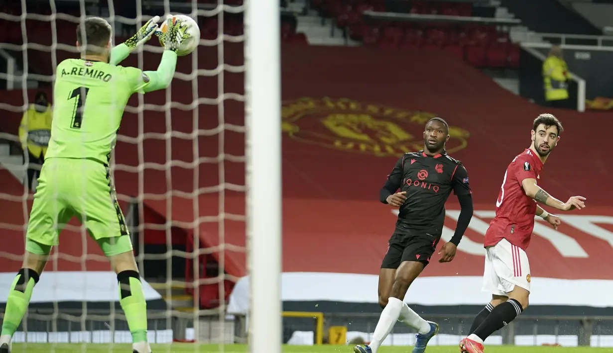 Kiper Real Sociedad, Alex Remiro berhasil menangkap bola tendangan gelandang Manchester United, Bruno Fernandes (kanan) dalam laga leg kedua babak 32 Besar Liga Europa 2020/21 di Old Trafford Stadium, Kamis (25/2/2021). Real Sociedad bermain imbang 0-0 dengan Manchester United. (AP/Dave Thompson)