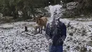 Seorang pria bermain dengan salju di sebuah peternakan di pedesaan Sao Joaquim, Brasil, selatan, Kamis (29/7/2021).  Sementara Amerika Utara menderita musim panas yang luar biasa panas, Amerika Selatan mengalami musim dingin yang tidak normal. (AP Photo/Mycchel Legnaghi)