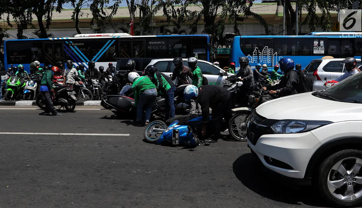 Sejumlah pengendara bergotong royong mengangkat sepeda motor mereka melewati pembatas jalan untuk berpindah jalur di kawasan Ridwan Rais, Jakarta, Rabu (21/8/2019). Pengendara motor tersebut berpindah jalur disebabkan tidak sabar menunggu kemacetan. (Liputan6.com/Johan Tallo)