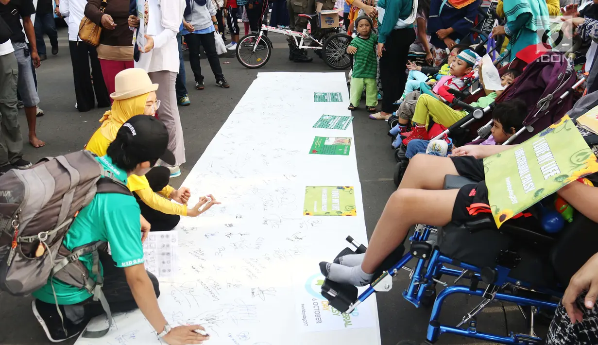 Masyarakat membubuhkan tanda tangan pada Peringatan Hari Cerebral Palsy Sedunia di area Car Free Day, Bundaran HI, Jakarta, Minggu (8/10). Kegiatan tersebut untuk menggalang kepedulian bagi penyandang Cerebral Palsy. (Liputan6.com/Angga Yuniar)