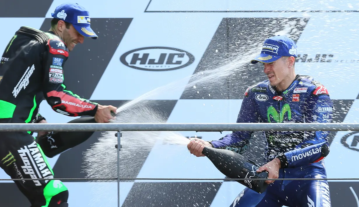 Pembalap Movistar Yamaha dan Tim Yamaha Tech 3, Maverick Vinales dan Johann Zarco saling menyemprotkan sampanye di podium MotoGP Prancis, Minggu (21/5). Vinales menjuarai MotoGP Prancis disusul Zarco yang menempati posisi kedua. (AP Photo/David Vincent)