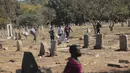 Pedagang Zimbabwe membawa dagangannya di kuburan setelah kabur dari kejaran polisi yang mengejar mereka setelah kedapatan berjualan dari tempat yang tidak ditentukan karena pembatasan COVID-19 di Harare, Kamis (29/7/2021). (AP Photo/Tsvangirayi Mukwazhi)