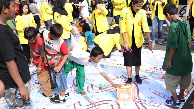 Mahasiswa jurusan Kriminologi Fisip UI mendampingi anak-anak bermain ular tangga saat gelaran Car Free Day di kawasan Bundaran HI, Jakarta, Minggu (18/11). Permainan ini bertujuan mengurangi anak-anak bermain gawai. (Liputan6.com/Helmi Fithriansyah)