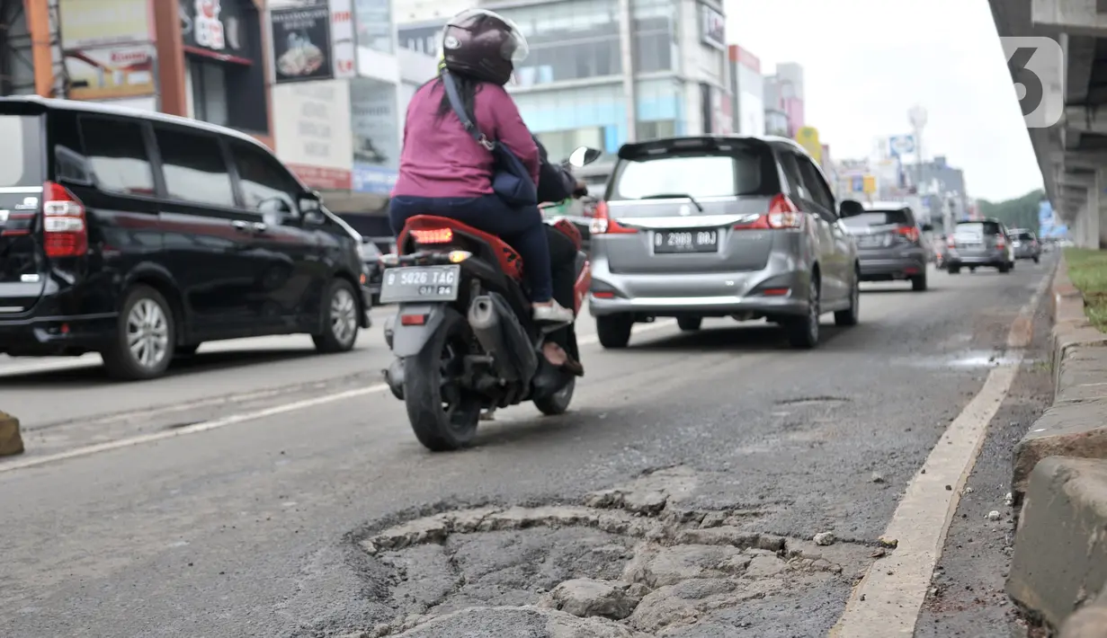 Kendaraan melintas dekat jalan berlubang di kawasan Kelapa Gading, Jakarta, Minggu (1/3/2020). Kepala Dinas Bina Marga DKI Jakarta Hari Nugroho mengatakan banjir pada Februari 2020 merusak 495 jalan Ibu Kota dengan 3.290 titik lubang yang tersebar di lima wilayah. (merdeka.com/Iqbal Nugroho)
