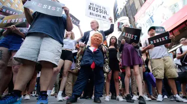 Seorang pendemo (tengah) membawa boneka berwajah Presiden AS, Donald Trump dalam demontrasi di Times Square, New York, Rabu (26/7). Demonstrasi digelar setelah Trump melarang kaum transgender menjadi personel militer AS. (AP/Frank Franklin II)