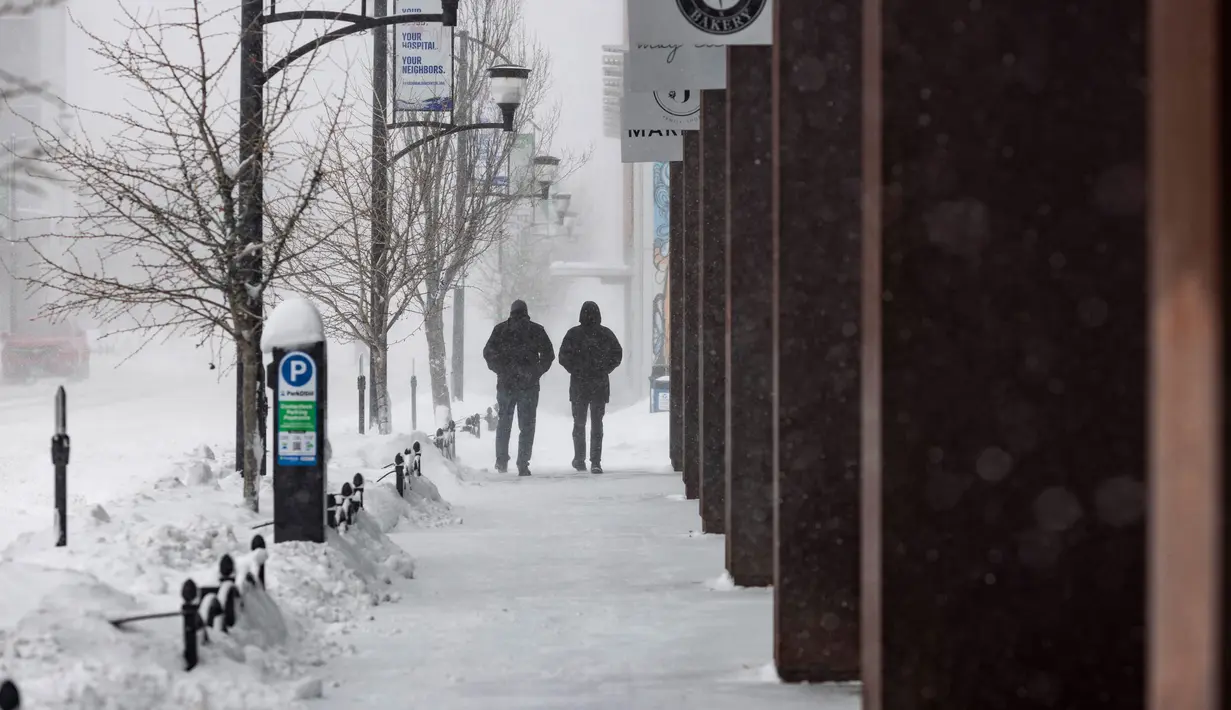 Orang-orang berjalan saat terjadi badai salju di lingkungan East Village, Des Moines, Iowa, pada tanggal 12 Januari 2024. (Christian MONTERROSA/AFP)