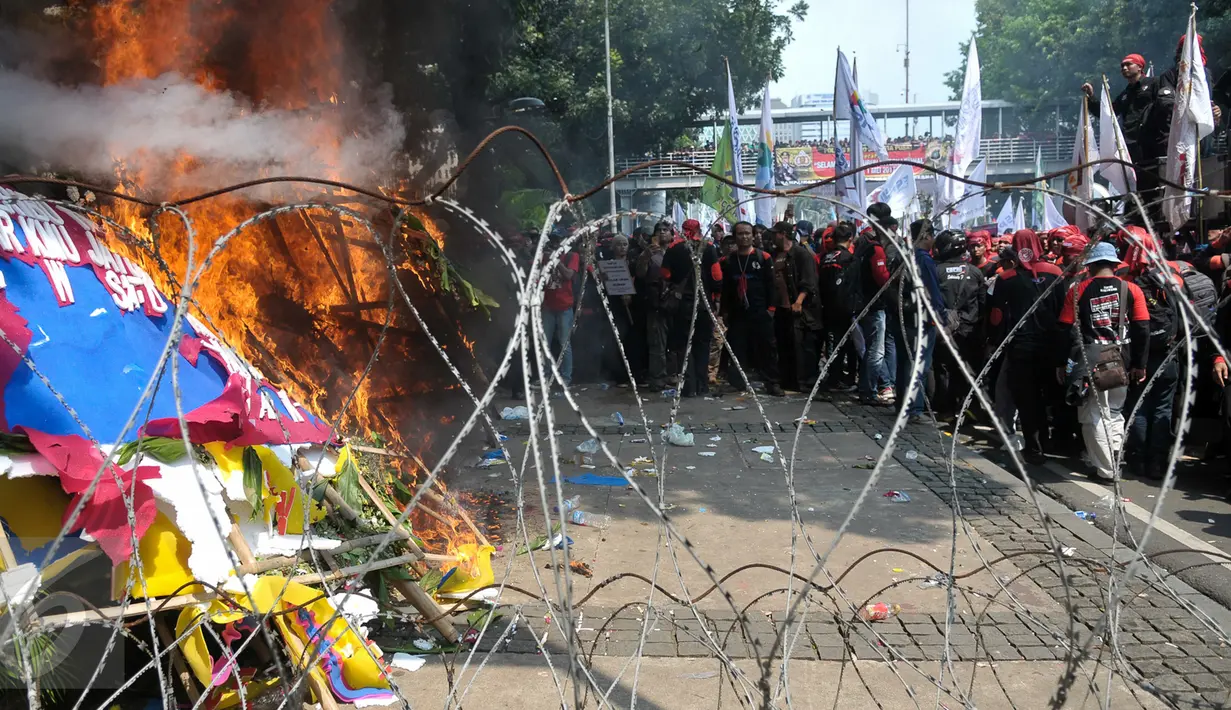 Karangan bunga untuk Ahok-Djarot dibakar oleh orang yang diduga menjadi provokasi saat aksi Hari Buruh di Jalan Medan Merdeka Barat, Jakarta, Senin (1/5). (Liputan6.com/Yoppy Renato)