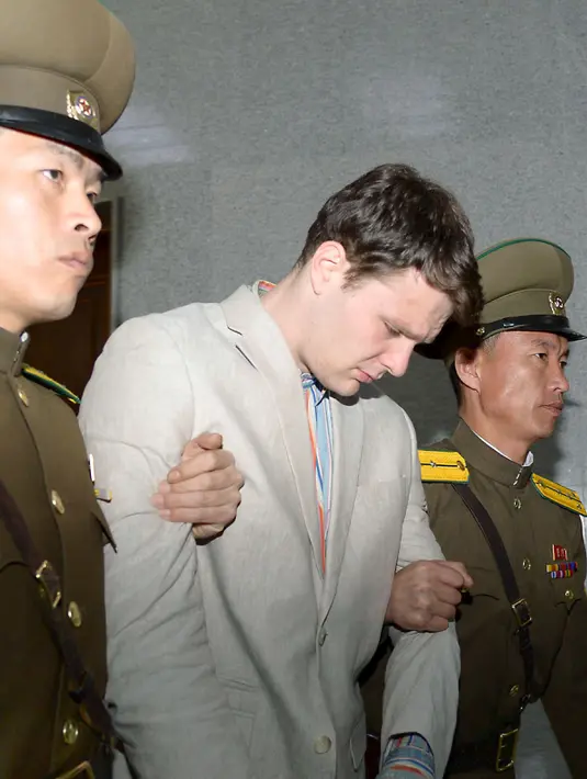 Mahasiswa University of Virginia, Otto Frederick Warmbier (tengah) saat digelandang oleh petugas keamanan Korea Utara di Pyongyang, (16/3). Ia didakwa karena sengaja mencuri pamflet berisi pesan propaganda pemerintah Korut di hotelnya. (REUTERS / Kyodo)
