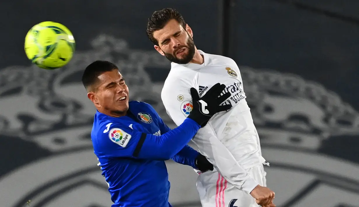 Bek Real Madrid, Nacho Fernandez (kanan) berduel udara dengan striker Getafe, Cucho Hernandez dalam laga lanjutan Liga Spanyol 2020/21 pekan ke-22 di Alfredo di Stefano Stadium, Selasa (9/2/2021). Real Madrid menang 2-0 atas Getafe. (AFP/Gabriel Bouys)