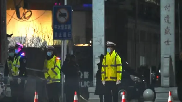 Polisi berdiri di luar sekolah tempat 13 orang tewas dalam kebakaran di Yanshanpu Provinsi Henan, China tengah pada 20 Januari 2024. (AFP/Greg Baker)