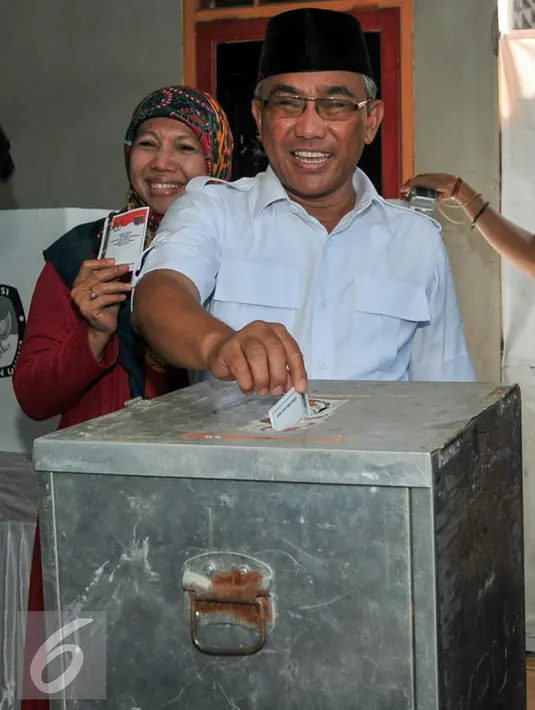 Calon Walikota Depok, Mohammad Idris dan istri memasukkan surat suara kedalam kotak di TPS 077 di Perum Pondok Duta, Sukmajaya, Depok, (9/12). Mohammad Idris diusung oleh Partai Keadilan Sejahtera (PKS) dan Partai Gerindra. (Liputan6.com/Yoppy Renato)