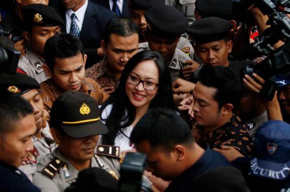 Angelina Sondakh tersenyum saat dikawal petugas keamanan KPK dan polis 