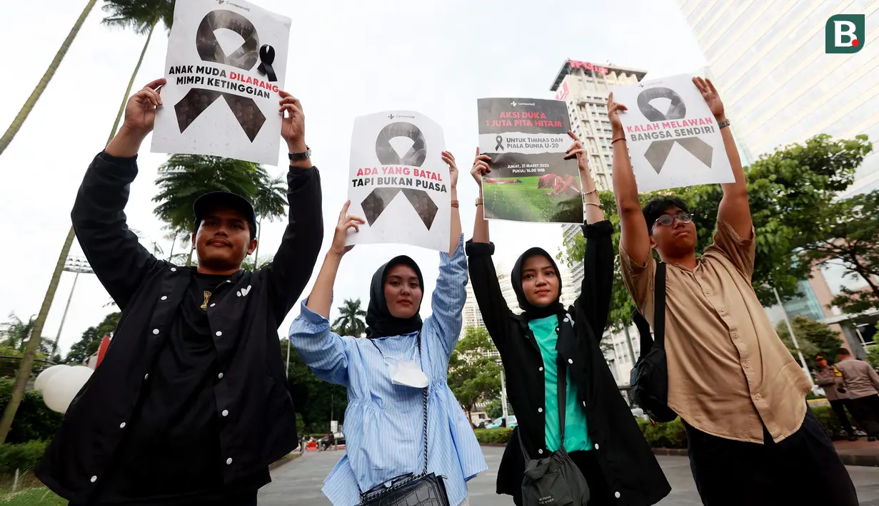 Perwakilan komunitas Centennialz membentangkan poster dalam Aksi Duka 1 Juta Pita Hitam untuk Timnas Indonesia U-20 dan Piala Dunia U-20 di trotoar FX Sudirman, Jakarta, Jumat (31/3/2023). (Bola.com/M Iqbal Ichsan)