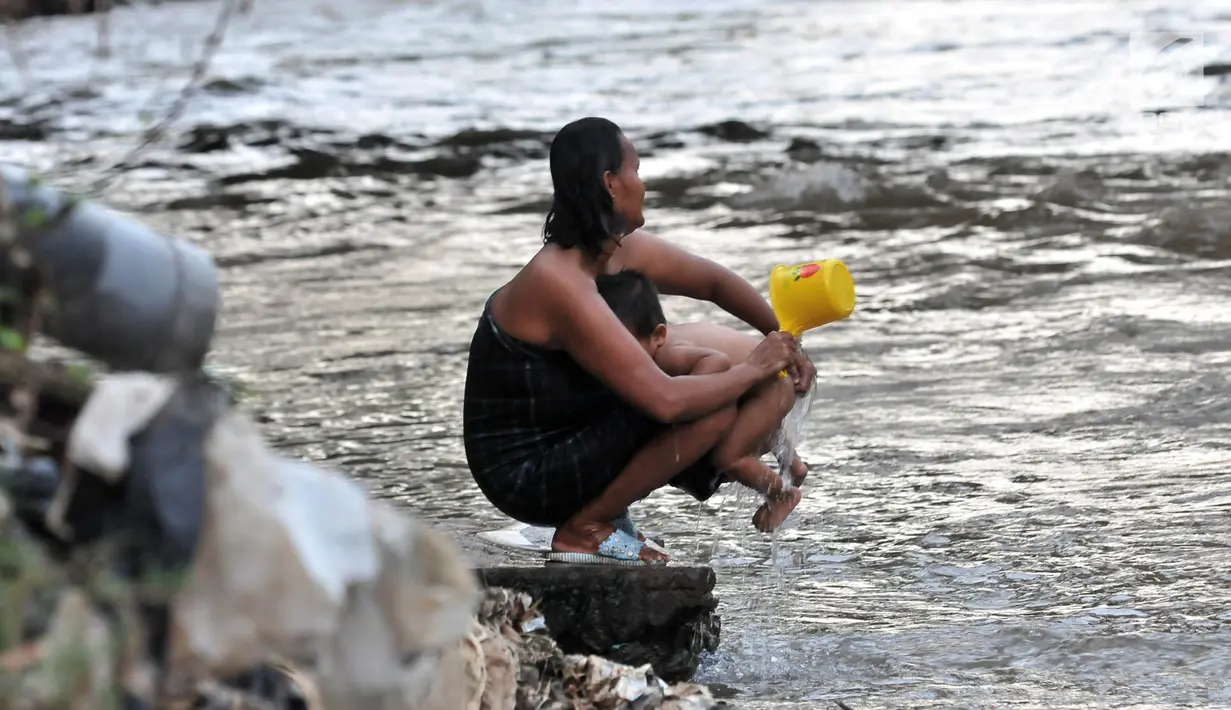 Warga menyeboki anaknya di bantaran Kali Ciliwung, Jakarta, Senin (19/11). Tak adanya akses sanitasi yang layak menyebabkan anak-anak menderita stunting. (Merdeka.com/Iqbal Nugroho)