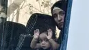 Seorang anak imigran terlihat di jendela bus selama operasi polisi di pusat Athena, Yunani (19/9/2019). Polisi di Athena pada 19 September 2019 memindahkan lebih dari 200 migran, termasuk lusinan anak-anak, dari dua tempat di pusat kota sebagai bagian dari pembersihan. (AFP Photo/Louisa Gouliamaki)