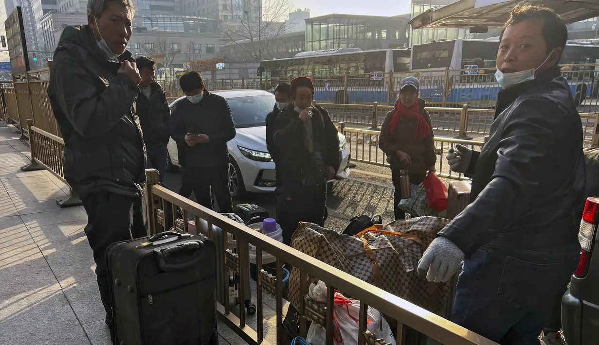 Buruh migran dengan barang bawaannya beristirahat di luar Stasiun Kereta Api Barat sebelum naik kereta di Beijing, Jumat (6/1/2023). China berupaya meminimalkan kemungkinan wabah COVID-19 yang lebih besar selama kesibukan perjalanan Tahun Baru Imlek bulan ini menyusul berakhirnya sebagian besar langkah-langkah pencegahan pandemi. (AP Photo/Wayne Zhang)