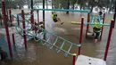 Orang-orang bermain dengan peralatan di taman bermain di tepi Sungai Nepean di Jamisontown di pinggiran barat Sydney (22/3/2021). Banjir membuat  ribuan orang mengungsi dari rumah mereka karena hujan masih melanda wilayah tersebut. (AP Photo/Mark Baker)