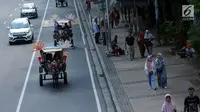 Delman hias membawa penumpang melintasi Jalan Medan Merdeka Barat, Jakarta, Selasa (19/6). Masa libur Lebaran 2018 dimanfaatkan sejumlah warga untuk berwisata di sekitar Monumen Nasional dengan menaiki delman hias. (Liputan6.com/Helmi Fithriansyah)