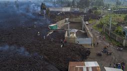 Warga melihat lava dari letusan Gunung Nyiragongo membelah Buhene di utara Goma, Kongo (24/5/2021). Gunung Nyiragongo mengirimkan aliran lahar ke desa-desa smenyebabkan sedikitnya 15 orang tewas di tengah kekacauan dan menghancurkan lebih dari 500 rumah. (AP Photo/Justin Kabumba)